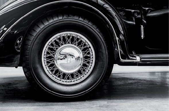 A close up of wheel disk and the side of a vintage automobile.